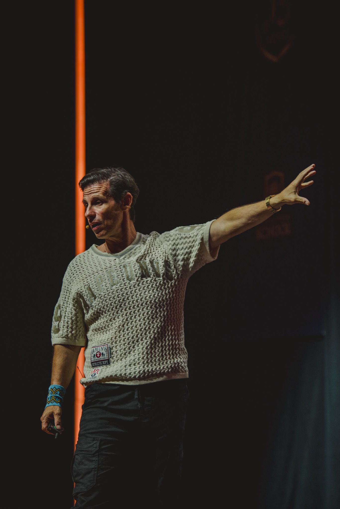 Palestrante em palco de evento corporativo com iluminação dramática